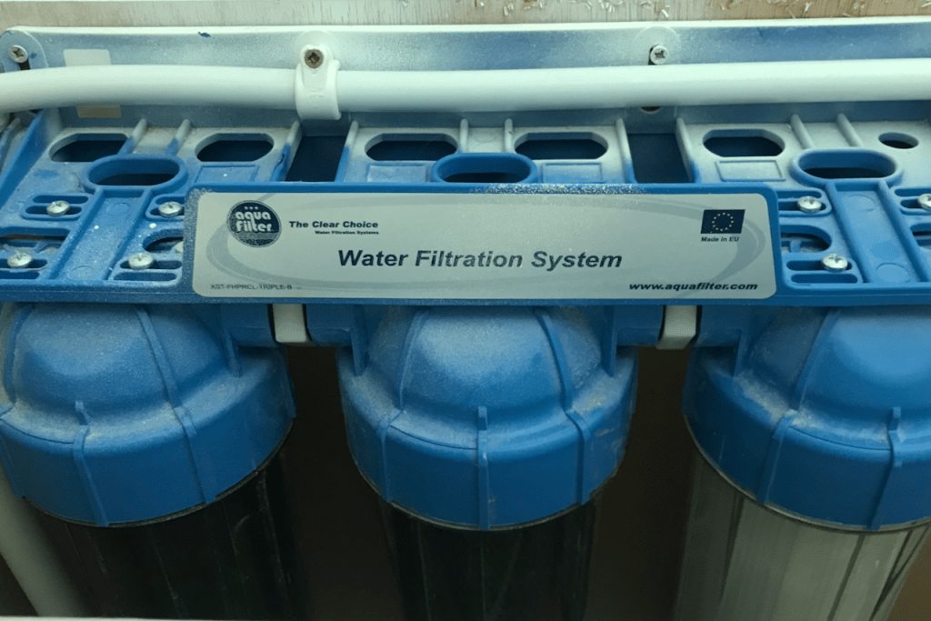 Image of a three phase water filtration system. with three cylinders side by side connected by a pipe across the top.