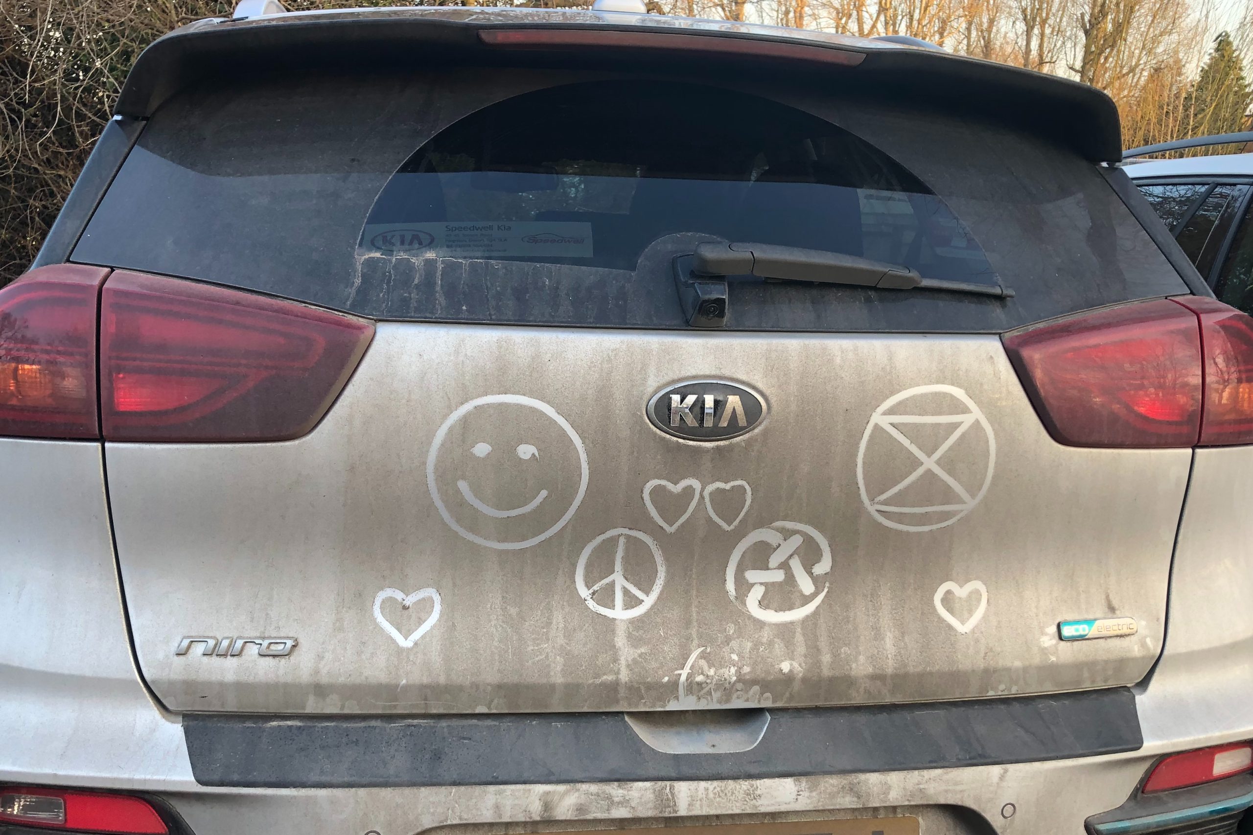 The back of our car with a few logos written in the dirt, including an XR symbol, a smiley face, a peace sign and a rolling A.