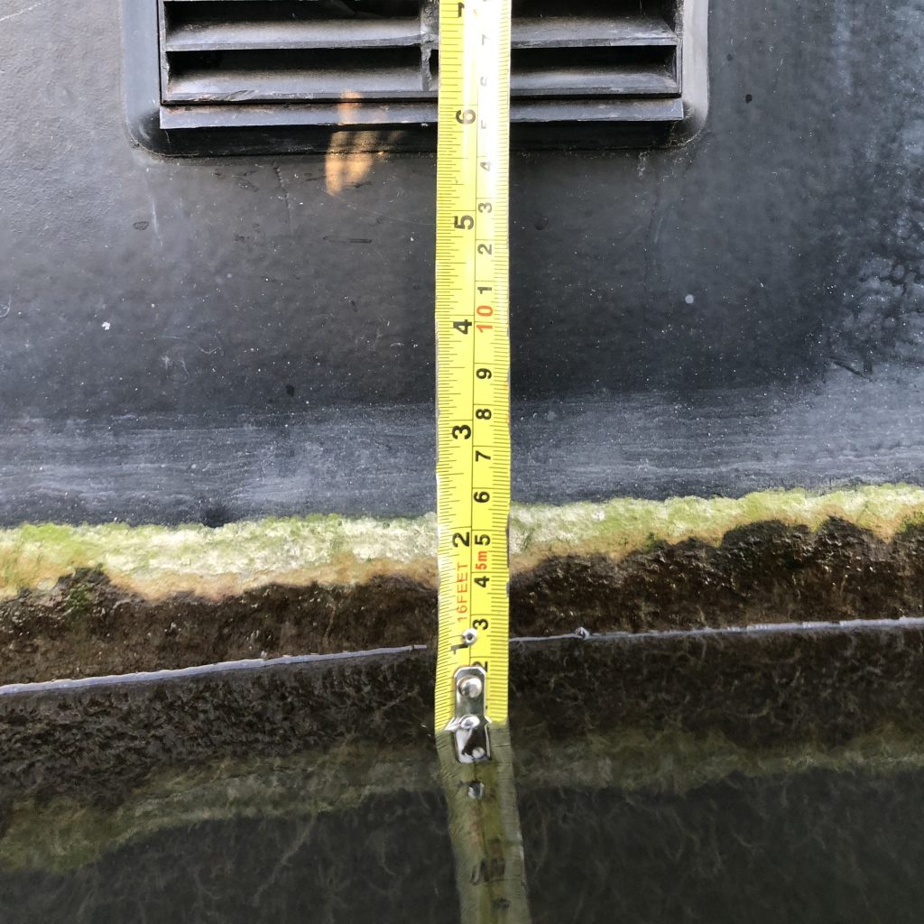 Image of the side of a boat with a vent at the top and a tape measure showing the distance from the water line is 15cm.
